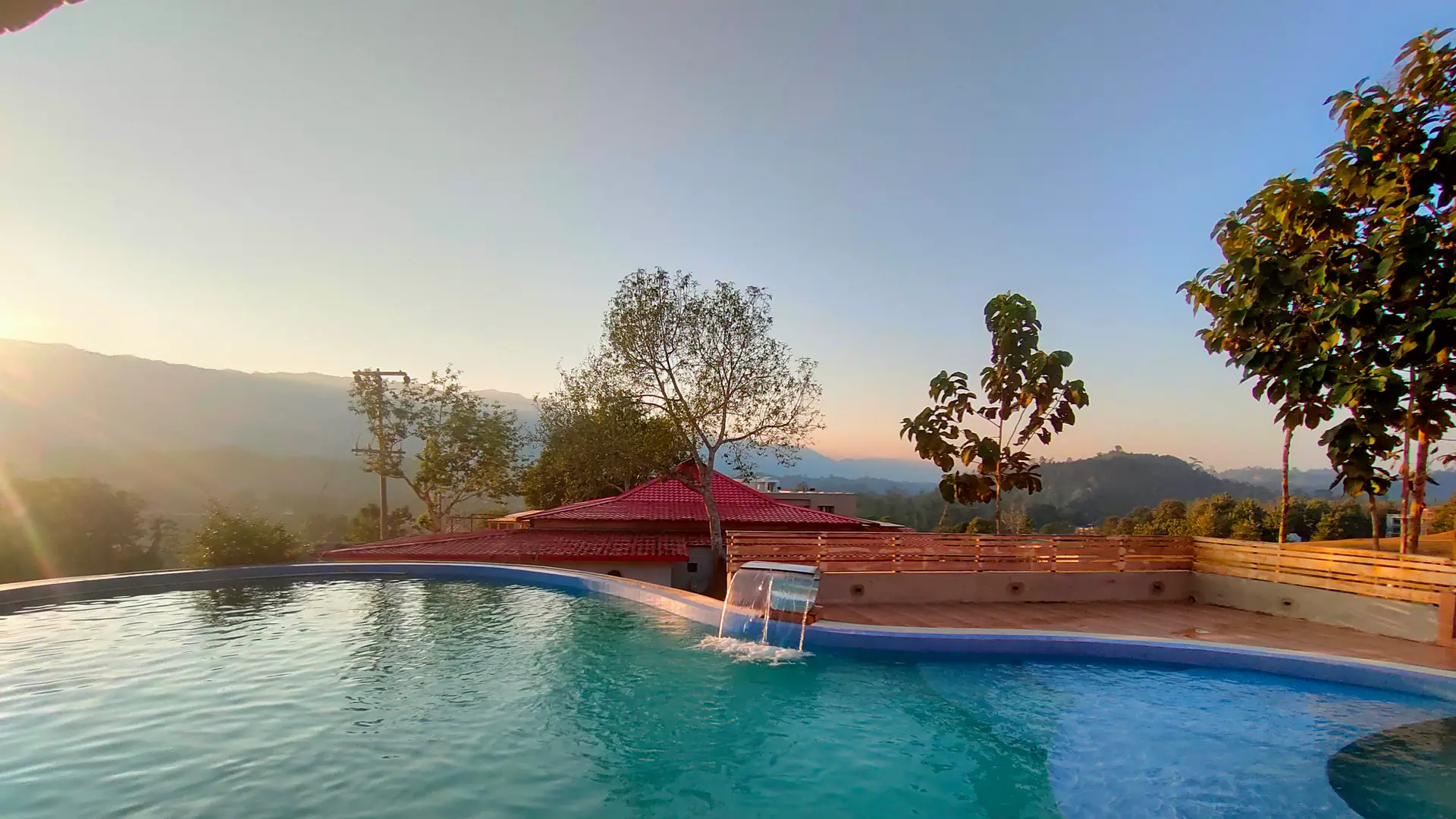 An infinity pool at sunset, overlooking green hills
