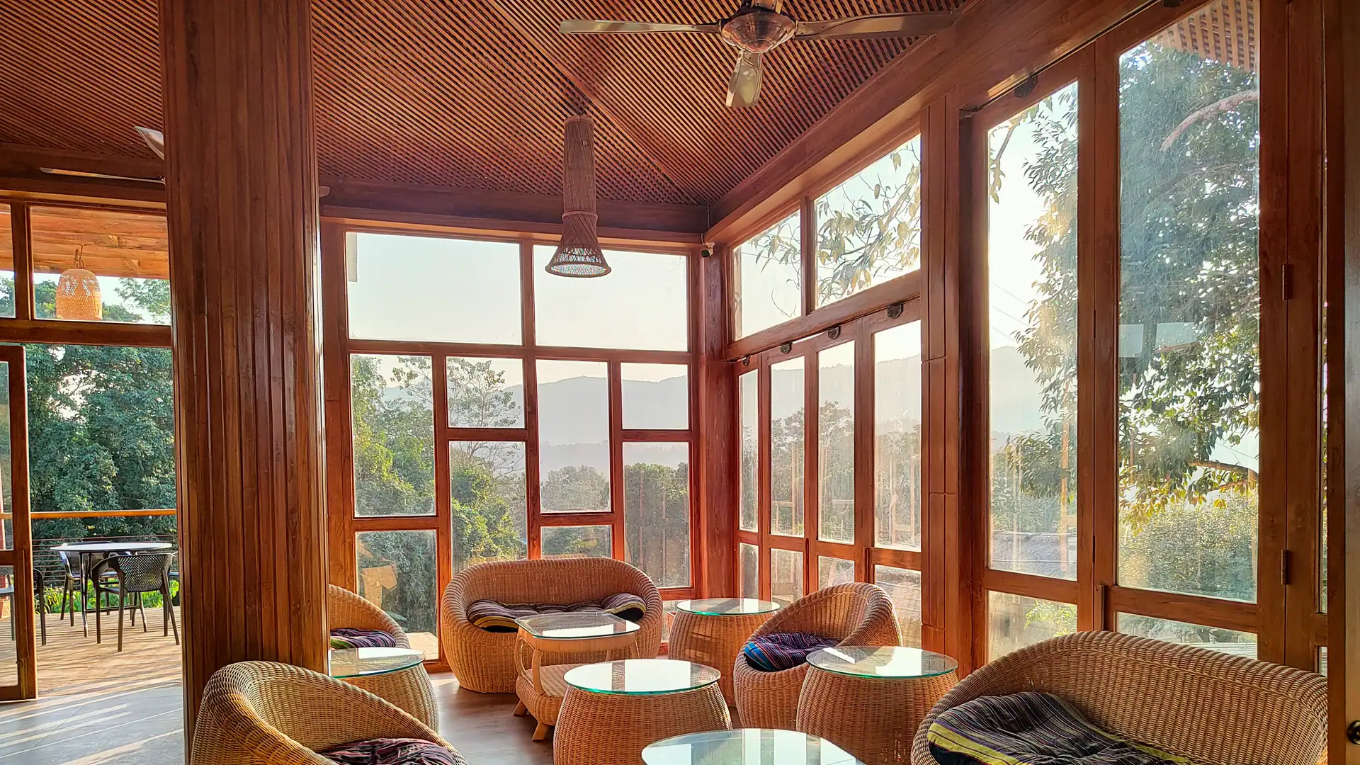 A glass-walled lounge with wicker seating and a wooden ceiling