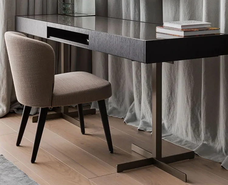 A dark wood desk and an upholstered chair beside long curtains