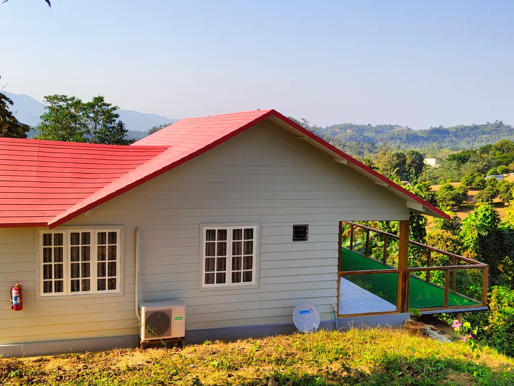 A cottage with a red roof on a green hillside